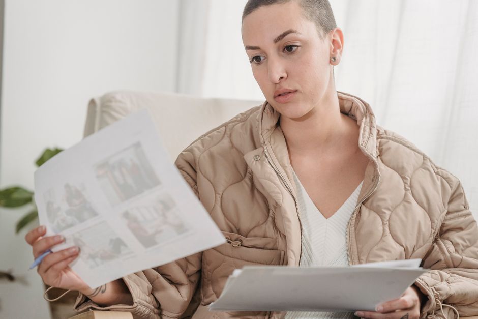 A bald woman focuses on reviewing papers indoors, showcasing a professional setting.